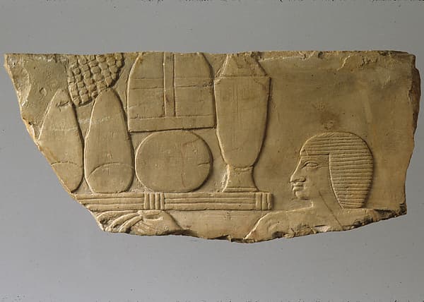 Raised relief fragment with head of an offering bearer and offerings
