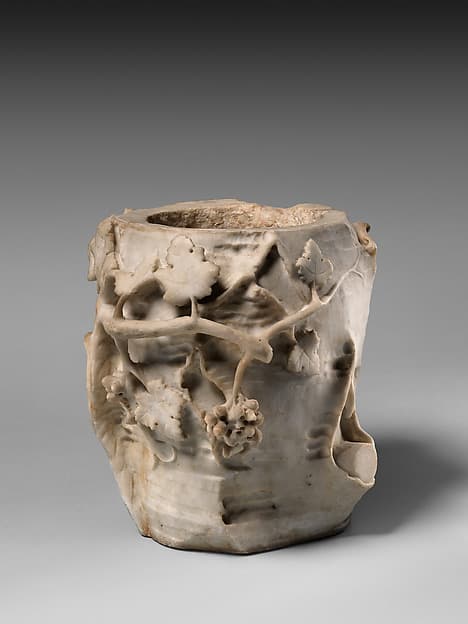 Marble cinerary urn in the form of a tree stump with leaves and grapes