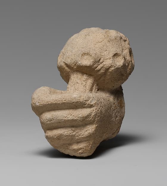 Limestone statue fragment of a left hand holding a bunch of daisies