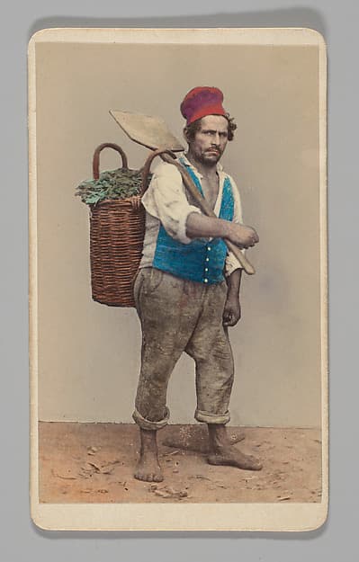 [Studio Portrait: Man Carrying Shovel and Basket of Greens], by Unknown