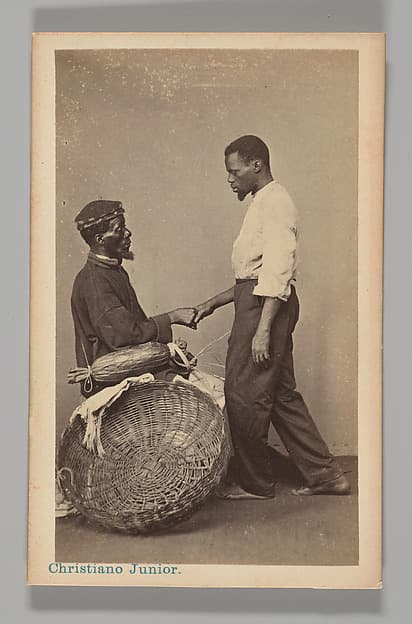 [Studio Portrait: Two Male Street Vendors in Profile, one Seated one Standing, Shaking Hands, Brazil], by Christiano Junior