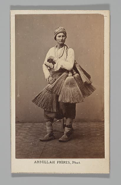 [Studio Portrait: Person with Brooms, Syria], by Abdullah Frères