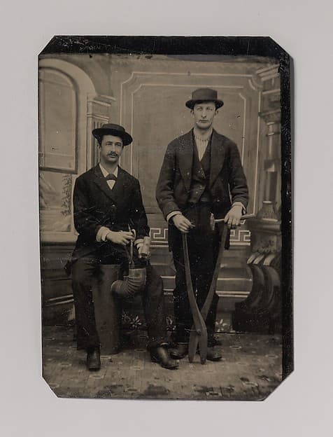 [Two Stovepipe Makers, One with a Hammer and Tin Snips, the Other Sitting on Stovepipe Assembly with Tin Snips and Mallet], by Unknown