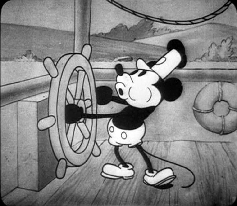 Black-and-white animation frame: Mickey Mouse standing at a riverboat’s ship wheel, whistling, with a life ring on the wall behind him.