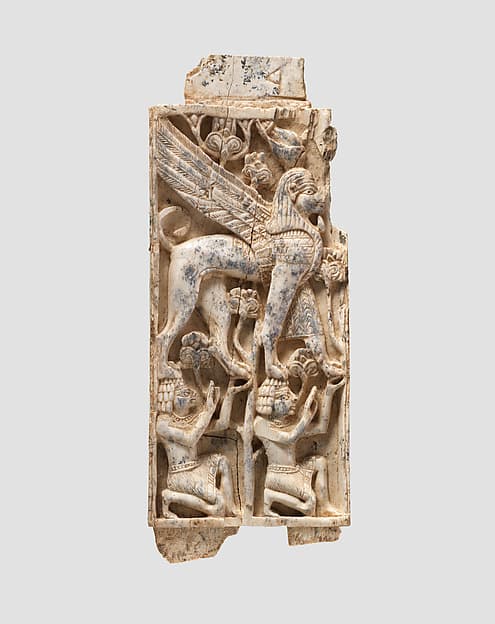 Furniture plaque carved in relief with a striding, falcon-headed winged sphinx supported by two kneeling figures
