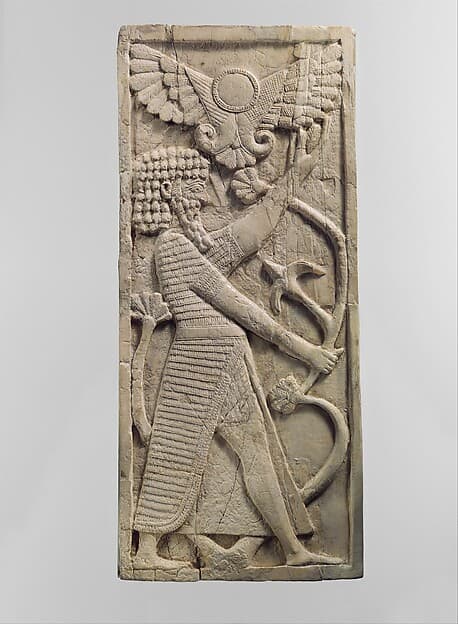 Furniture plaque carved in relief with a male figure grasping a tree; winged sun disc above