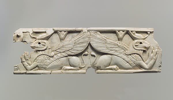 Furniture plaque carved in relief with two addorsed, ram-headed sphinxes