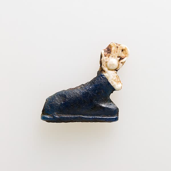 Amulet of kneeling cow wearing disk and feathers