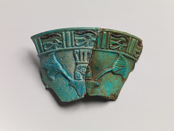 Relief chalice rim fragment with a wedjat frieze and below that a Hathor sistrum head emerging from papyrus plants (joined with 2010.9)