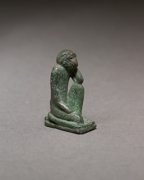 Monkey kneeling and resting its head in a hand