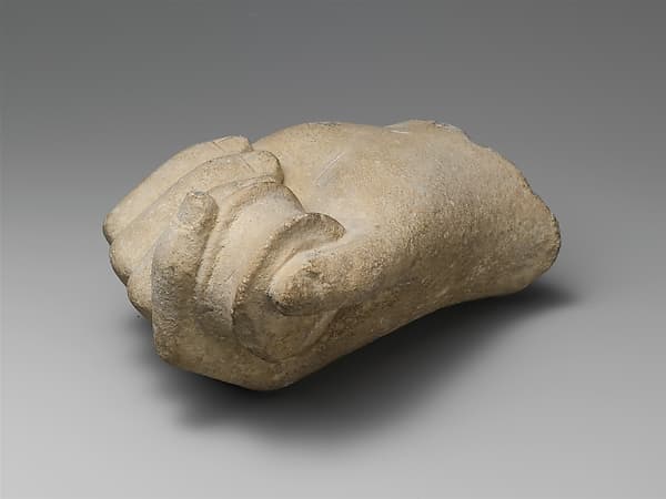Limestone statue fragment of a hand holding a pyxis or bobbin