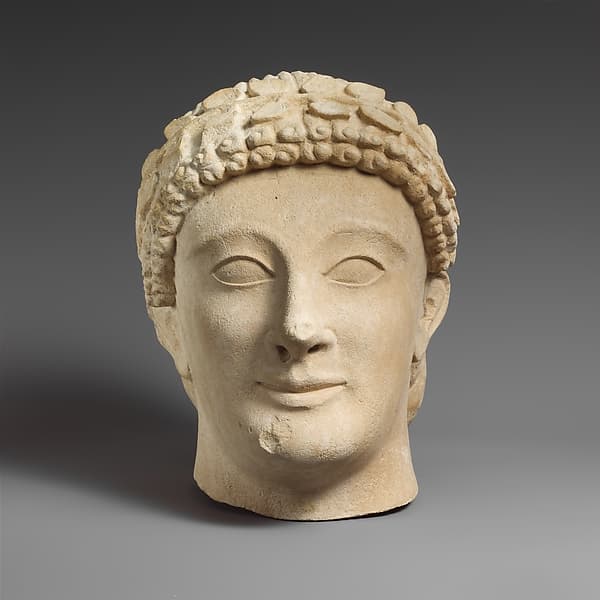 Limestone head of a beardless male votary with a wreath of leaves