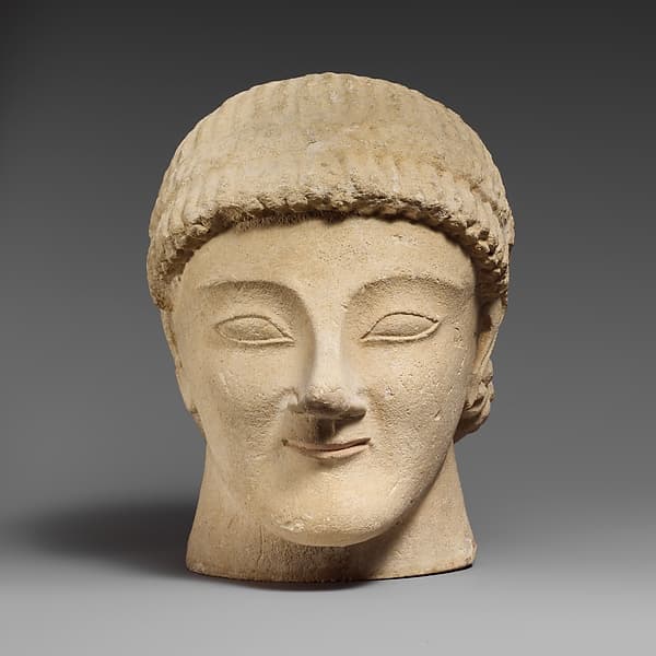 Limestone head of a beardless male votary with a wreath of rosettes
