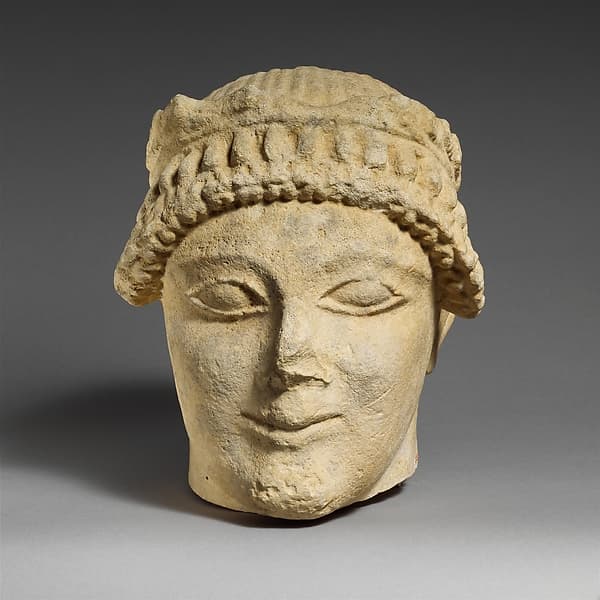 Limestone head of a beardless male votary with a wreath of leaves