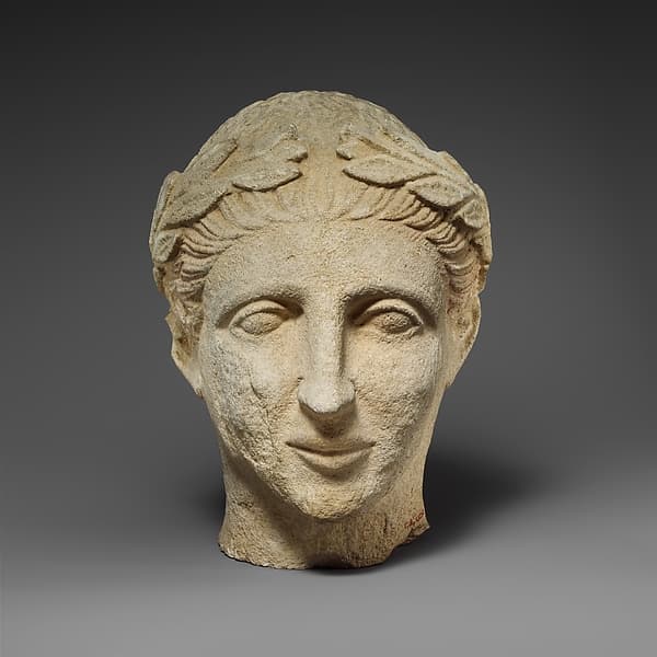 Limestone head of a beardless male votary with a wreath of leaves