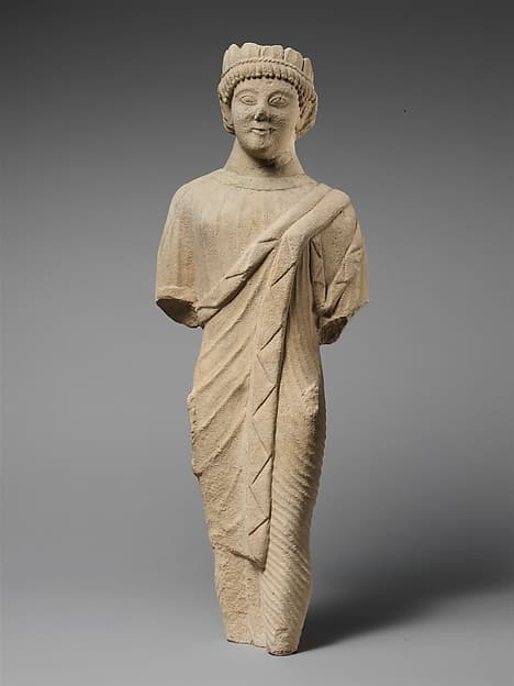 Limestone statuette of a beardless male votary in Greek dress with a wreath of leaves