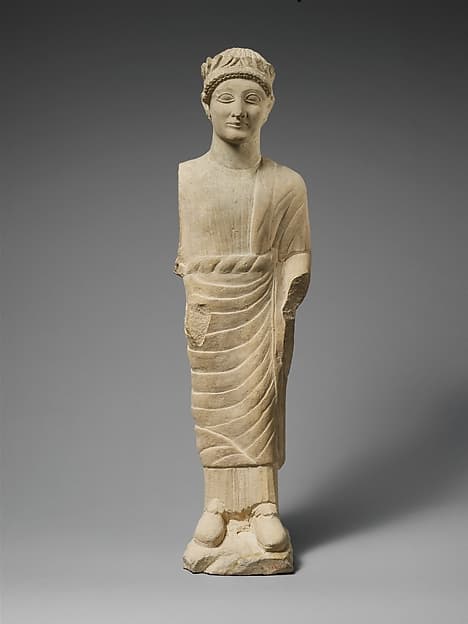 Limestone statuette of a beardless male votary with a wreath of leaves